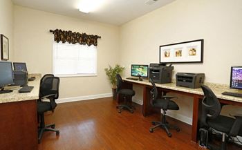 A room with a desk and chairs with a computer on it.